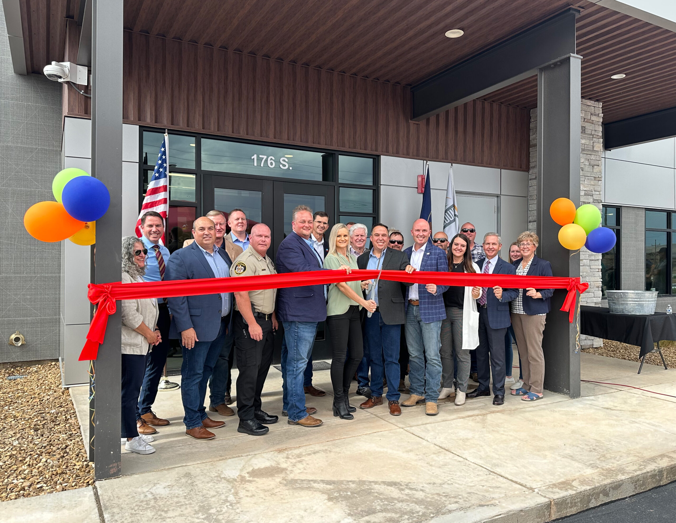 Crowd posing in front of the building behind the ribbon. 